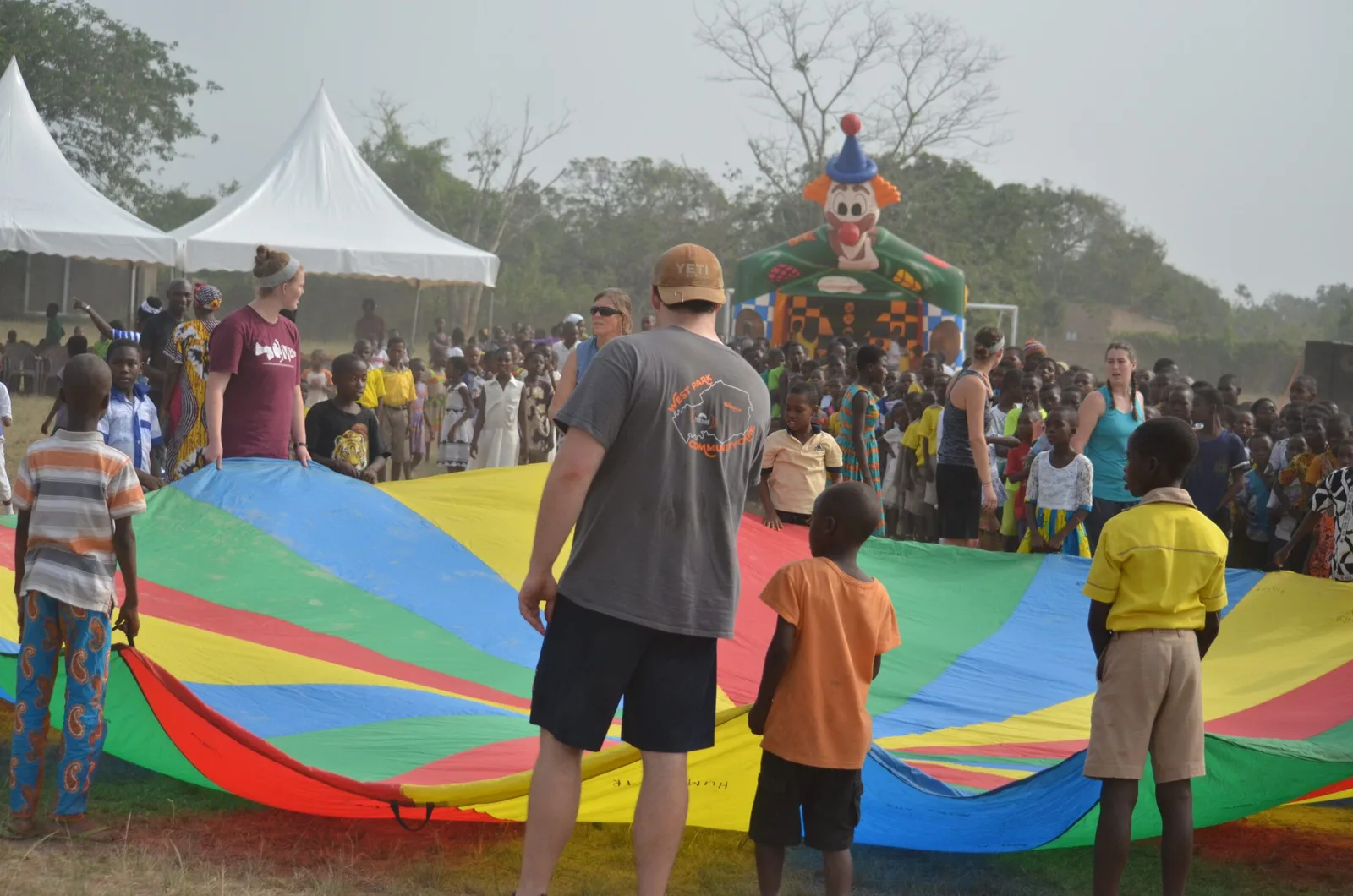A visiting summer team playing a parachute game with children in a Ghanaian community.